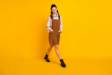 Fototapeta na wymiar Photo of lovely cute lady go hands wear brown overall pullover footwear isolated yellow color background