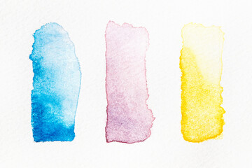 Watercolor paint swatches lined up in a grid on a white background, closeup, macro