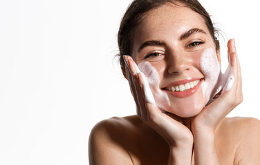 Cheerful female model applies foaming cleanser, has clean fresh healthy skin, smiles broadly, Girl...
