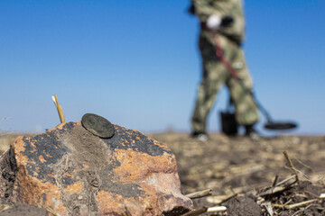 a man with a metal detector in the vast expanses of an old defensive fortress in search of ancient coins and artifacts, the foreground and background are blurred with bokeh effect