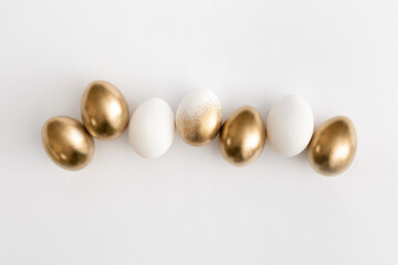 Golden eggs on a white background. Minimal easter concept.