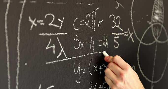 Hands closeup on chalk board writing formulas