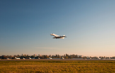 Passenger plane fly up over take-off runway from airport at sunrise. Private jet plane in the blue...