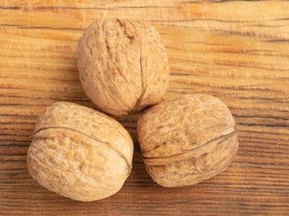 Three walnuts on brown wooden background