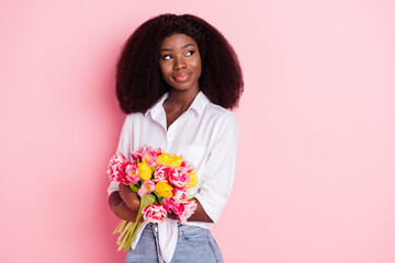 Photo of nice optimistic brunette hairdo lady hold flowers look empty space wear white shirt isolated on pink color background