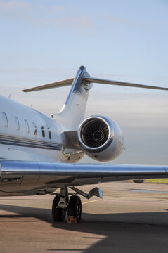 Business travel concept. Jet engine on parked luxury private jet. Rear detail with engine, tail-plane and windows of business-jet aircraft. Space for text.
