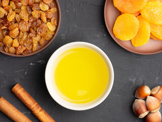 Cinnamon, dried apricots, raisins, nuts, honey on black concrete background