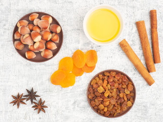 Obraz na płótnie Canvas Cinnamon, star anise, dried apricots, raisins, nuts, honey on white concrete background
