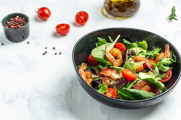 Fresh salad bowl with avocado and shrimps in bowl, Delicious breakfast or snack on a light background, top view