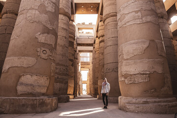 Young man gazing up in wonder at the massive columns at Karnak Temple in Luxor Egypt
