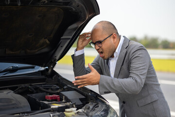 Fototapeta na wymiar Young asian business has broken down car. He open hood and check the engine. He feeling upset and stressed. Car broken on the side of the road