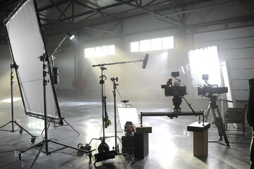 Fototapeta Profesional video studio.Behind-the-scenes of a video shooting.Behind the shooting production silhouette of camera and equipment in studio.Selective focus. obraz