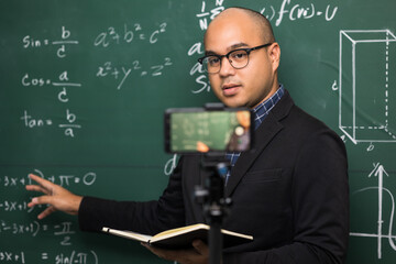 Indian young teacher man teaching online video conference live stream by smartphone. Asian teacher teaching mathematics class webinar online for students learning.