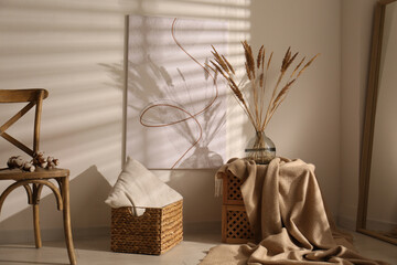 Vase with decorative dried plants and painting in stylish room interior