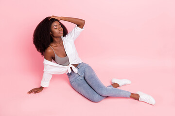 Full size photo of nice optimistic brunette hairdo lady lie down wear white shirt jeans sneakers isolated on pink color background