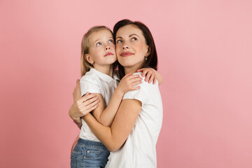 Happy woman and little girl, mother and daughter isolated over pink background.