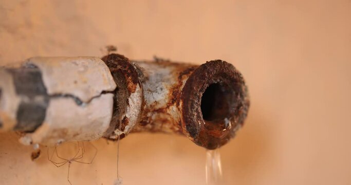 Water leaking from corroded pipe closeup footage