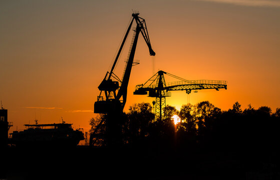 River boat and floating river cranes on the river bank at sunset