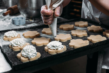 Chefs hands with pastry bag squeezing out cream dough for baking 