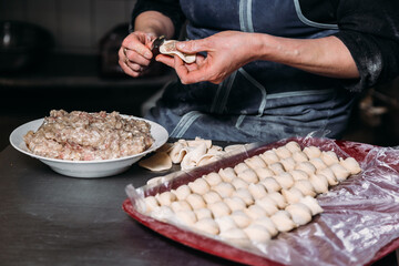 Chef's hands make dumplings from dough and ground beef 
