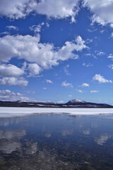 Fototapeta na wymiar 雲の浮かぶ青空と冬の終わりの湖。