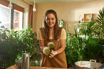 Girl with cacti in her hands is standing in garden © Svitlana