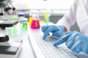 Scientist chemist typing on keyboard in laboratory closeup