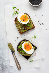 Healthy sandwich with avocado, eggs and microgreens on toast on a serving plate for breakfast. Healthy nutrition dietary concept. Top view