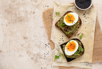 Healthy sandwich with avocado, eggs and microgreens on toast on a serving plate for breakfast. Healthy nutrition dietary concept. Top view