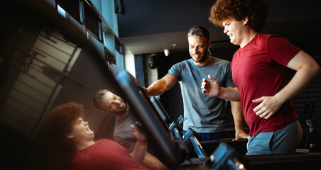Overweight young man exercising gym with personal trainer