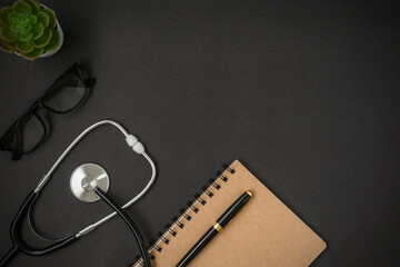 A stethoscope and notebook on black background with a copy space. Flat lay.