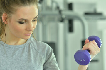Fototapeta premium Sporty young woman training with dumbbell in gym