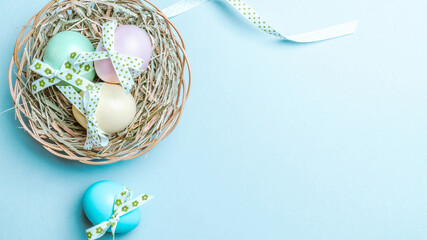 Easter flat. Colorful egg with tape ribbon on pastel blue background in Happy Easter decoration. Spring holiday top view concept.