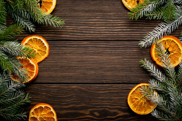 Fototapeta na wymiar Christmas or New Year background. Fir branches with dried orange, cardamom and mulled wine spices, sprinkledon dark wooden background. Place for your text