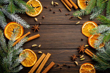Christmas or New Year background. Fir branches with dried orange, cardamom and mulled wine spices, sprinkledon dark wooden background. Place for your text