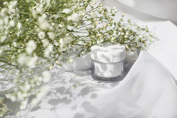 white cream jar side view. Organic cosmetology, natural cosmetics botanical concept. Women skin care product. Facial, body balm plastic container and foliage composition