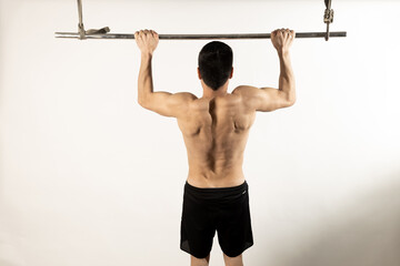 Fototapeta premium Athlete man doing pull-ups on white background.