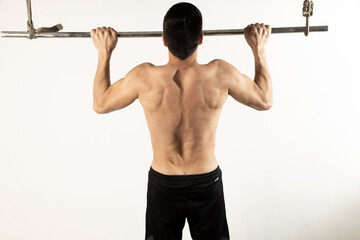 Athlete man doing pull-ups on white background.