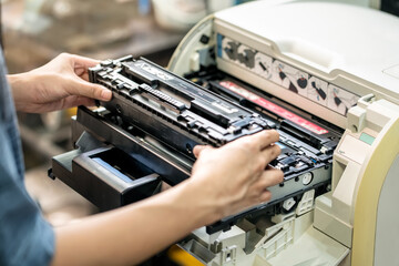 Women holding Laser toner cartridge ,replacing toner in laser printer at office. Repairs and...