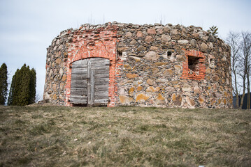 An abandoned windmill with wooden doors made of stones and bricks.