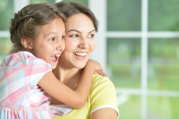 Close-up portrait of a charming little girl hugging with mom at home