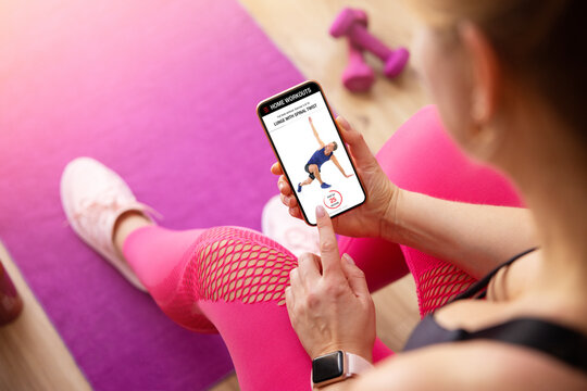 Woman uses fitness app on her phone for working out at home