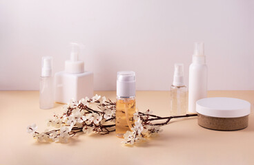 Fototapeta na wymiar Beauty product concept. Cosmetic containers and skin care products on light background and a branch of small white flowers