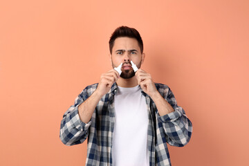 Man using nasal sprays on peach background