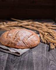 craft bread and ears of wheat on a dark wooden background, soft selective focus, vertical