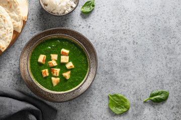 Palak Paneer served with basmati rice on grey stone background. Indian vegetarian cuisine made of spinach and paneer cheese. Copy space. View from above.