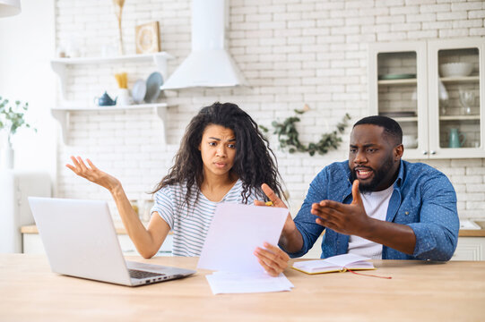 Anxious Mixed Race Couple Looking Through Domestic Bills, Reading Papers At Home, Worried Biracial Wife And African Husband Calculating Family Budget,not Enough Money On Bank Account To Repay The Loan