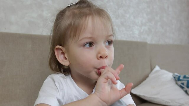 a large portrait of a little girl who sucks her finger in her mouth. Bad habits in children and adolescents.