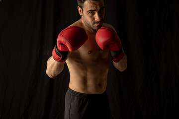 Fototapeta na wymiar athlete man training with boxing gloves on black background