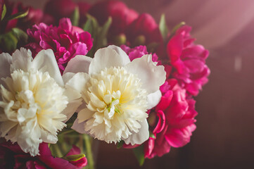 A colorful bouquet of peony flowers in a glass vase close up view.